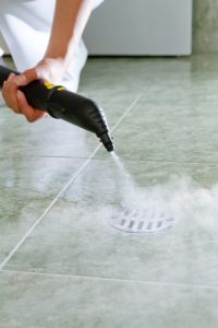 Woman cleaning drain in bathroom with steam