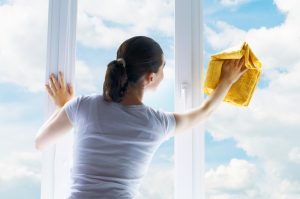 woman washing windows with clouds in the background